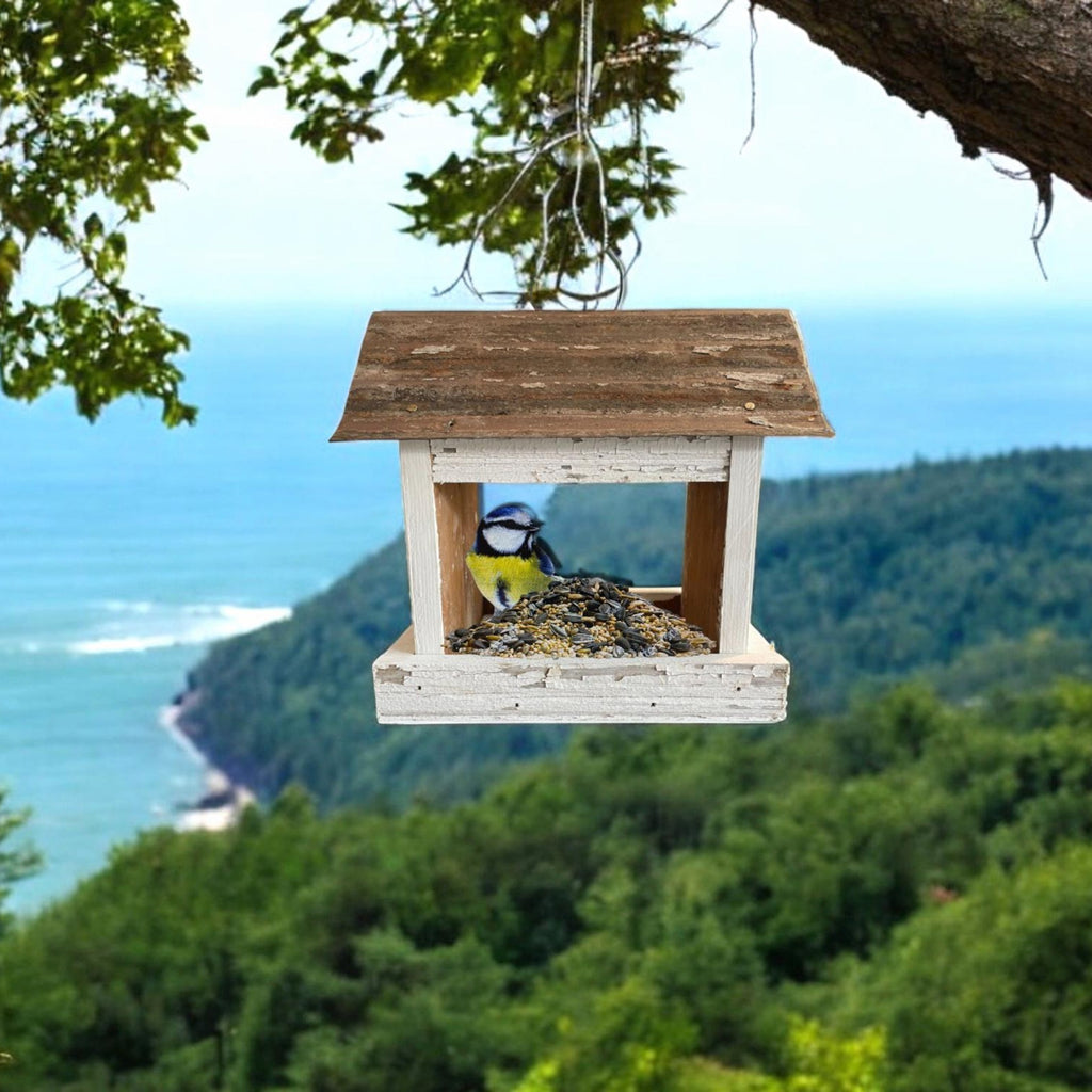 Rustic white wooden birdfeeder with a tin roof and star on both ends. Tray for easy feeding.