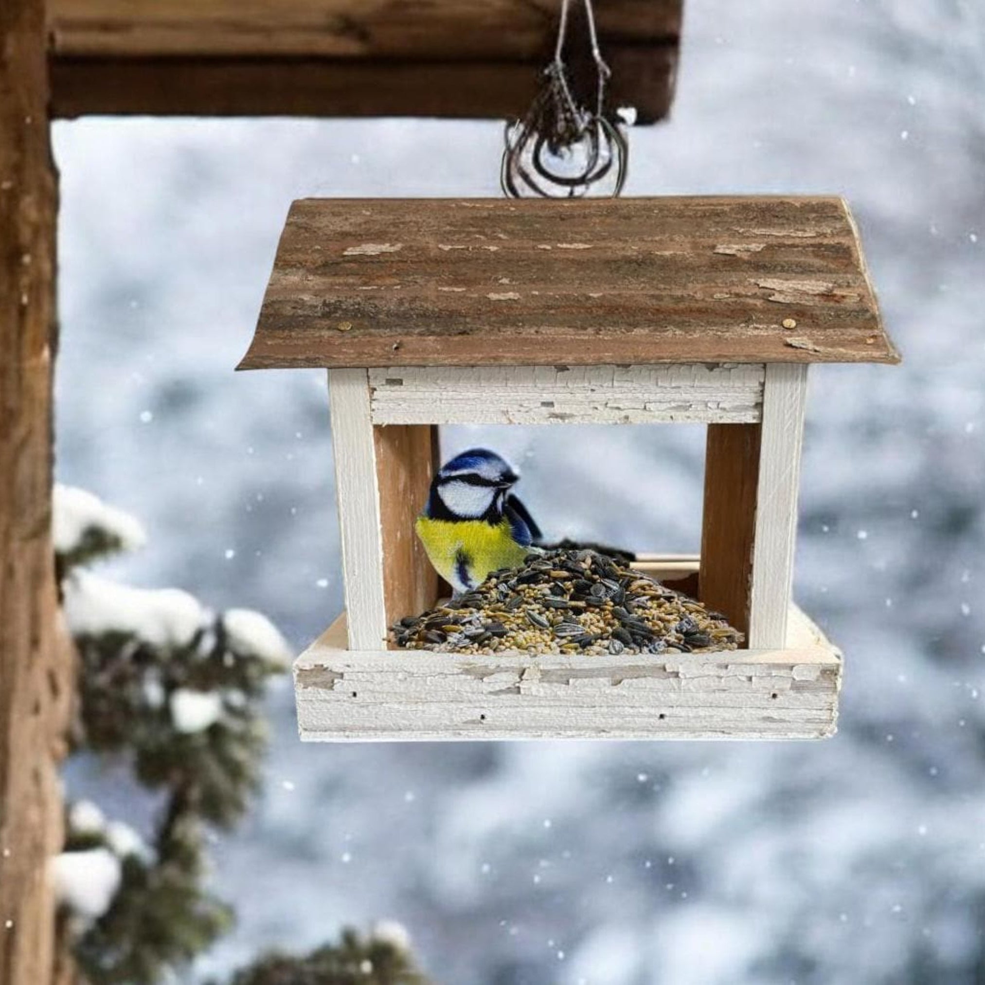 Rustic white wooden birdfeeder with a tin roof and star on both ends. Tray for easy feeding.