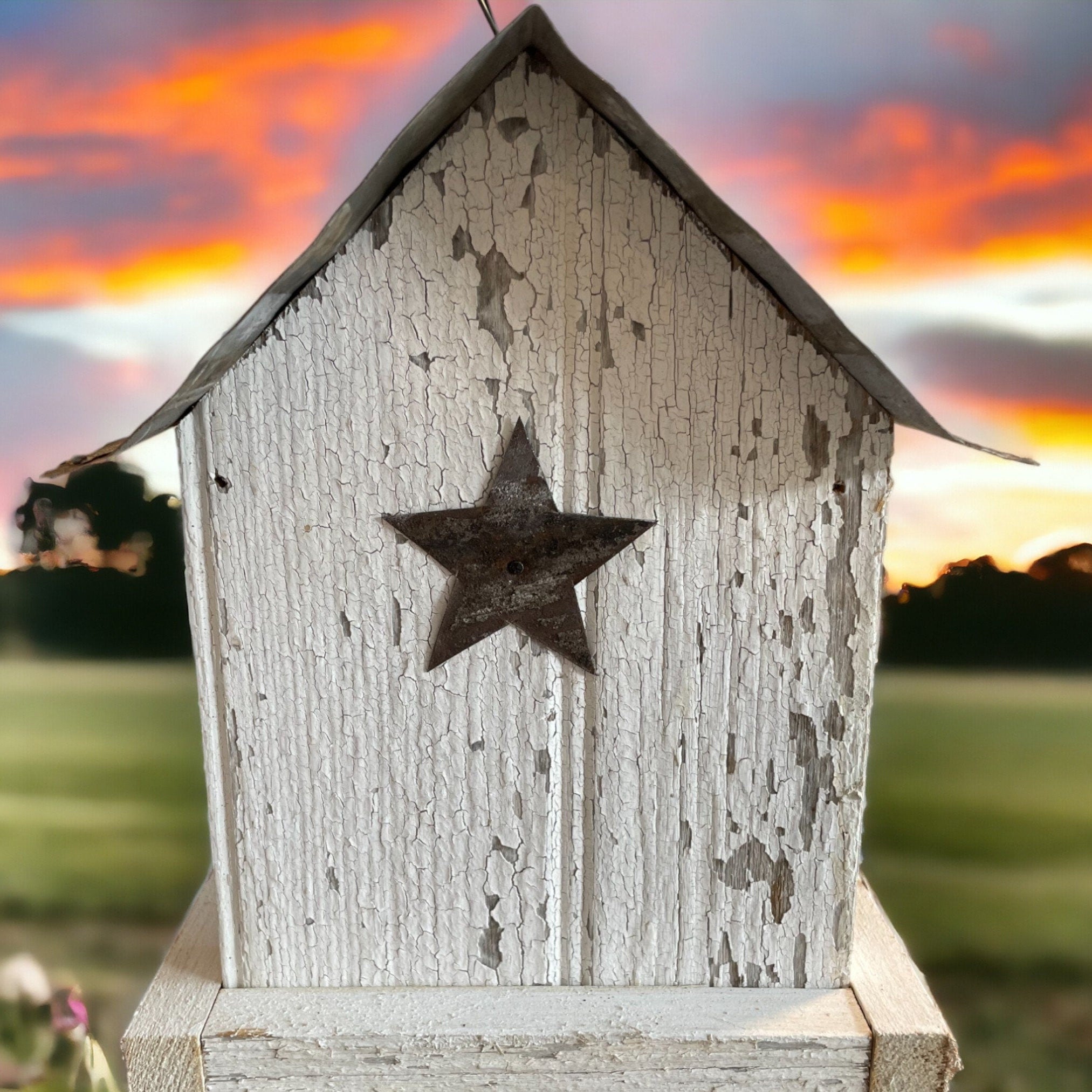 Rustic white wooden birdfeeder with a tin roof and star on both ends. Tray for easy feeding.