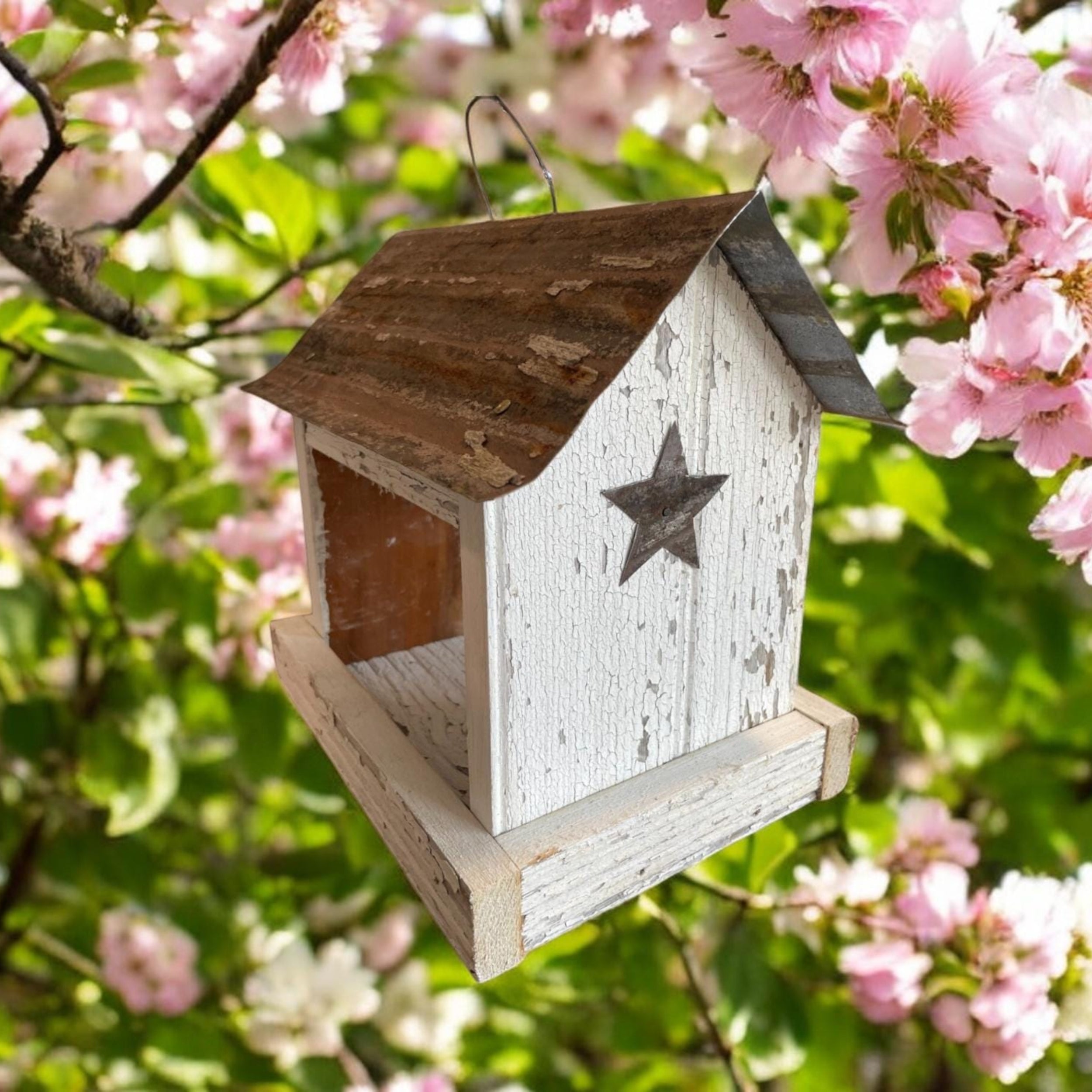 Rustic white wooden birdfeeder with a tin roof and star on both ends. Tray for easy feeding.