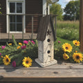 Wooden birdhouse with floral decorations on a wooden surface outdoors.